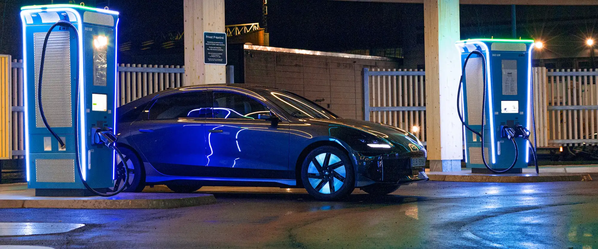 Electric sedan at a fast-charging station at night